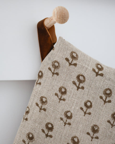 Acorn Blossom boho design stocking hanging against white paneled wall with velvet hanging loop and wooden peg