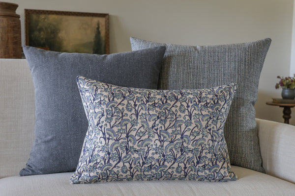Blue designer pillow covers styled on a cream sofa, featuring a blue floral block print lumbar pillow with textured blue and gray woven decorative throw pillows by HACKNER HOME.