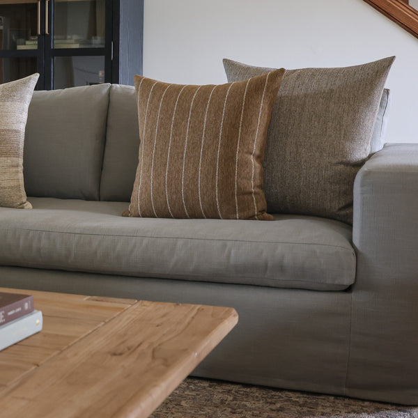 HACKNER HOME brown designer pillow covers styled on a neutral sofa, featuring a warm brown striped pillow layered with a textured herringbone throw pillow.