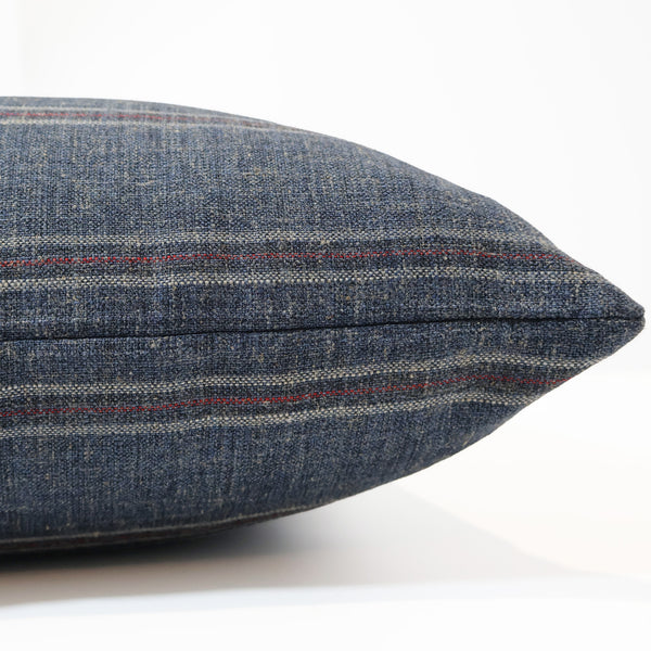 Foundry Stripe decorative pillow cover handcrafted from a premium polyester, acrylic, and linen blend upholstery fabric featuring deep indigo blue with ivory and muted brick pinstripes, luxury designer accent pillow for transitional, traditional, modern farmhouse, and contemporary interiors. Side view of cushion cover.