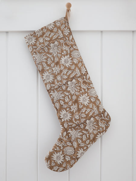 Rose Bud Brown Block Print Stocking, Large Design linen Christmas stocking with hand-printed cream floral and leaf motifs on a warm camel brown ground and a sand velvet hook, hanging from a wooden peg on a white paneled wall