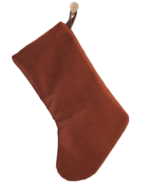 Boho Design rust-terracotta velvet Christmas stocking with a rounded foot and dark brown hanging strap, shown on a white background