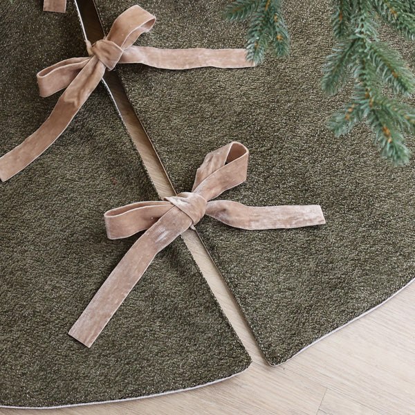Dark olive green textured velour Christmas tree skirt with taupe velvet ribbon bows, handmade in the USA and styled beneath an evergreen Christmas tree.