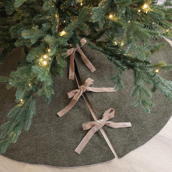 Dark olive green textured velour Christmas tree skirt with taupe velvet ribbon bows, handmade in the USA and styled beneath an evergreen Christmas tree.