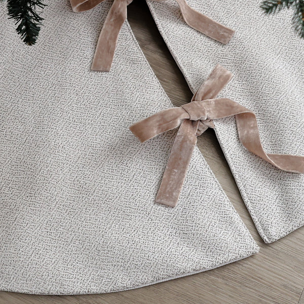 Handmade white velveteen Christmas tree skirt with subtle texture and double-sided velvet ribbon ties beneath an evergreen Christmas tree