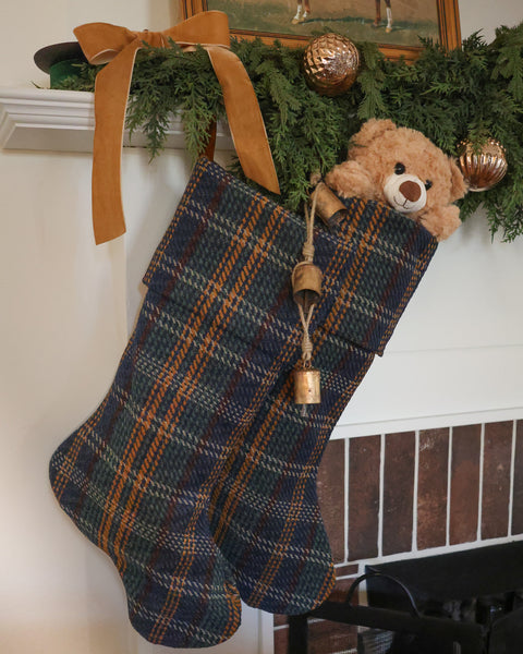 Luxury handmade blue tartan plaid Christmas stockings by HACKNER HOME, featuring Heritage cuff designs, a plush teddy bear, antique brass bells, and traditional Christmas mantel decor.