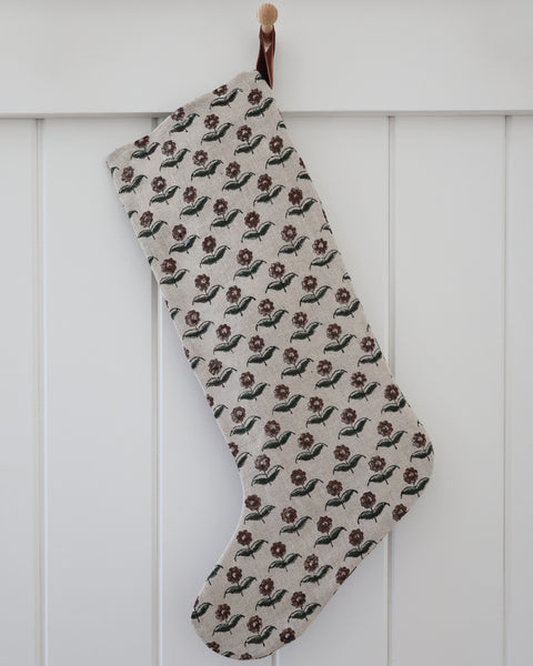 Vintage Rose Block Print Stocking, Large Design linen Christmas stocking with hand-printed deep burgundy blooms and olive green leaves on natural flax and a rust velvet hook, hanging from a wooden peg on a white paneled wall