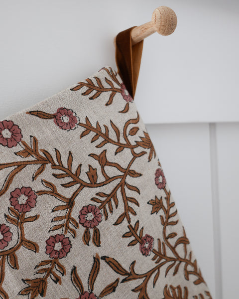 Close-up detail of Autumn Vine Linen Block Print Stocking showing caramel-brown vines, dusty rose blooms and black outlines on natural linen with a golden-brown velvet hanging loop