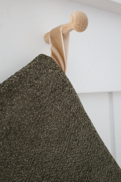 Close-up detail of Plush Dark Olive Green Stocking showing dense, plush dark olive texture with taupe flecks and a sand velvet hanging loop on a wooden peg