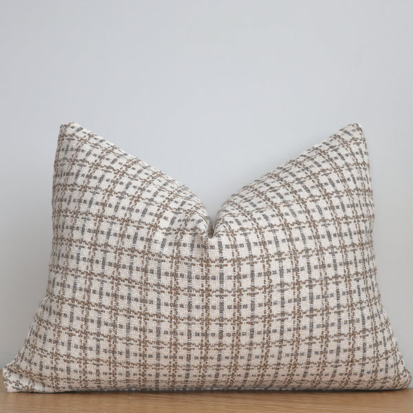 Plaid patterned pillow on a wooden surface with a light gray background