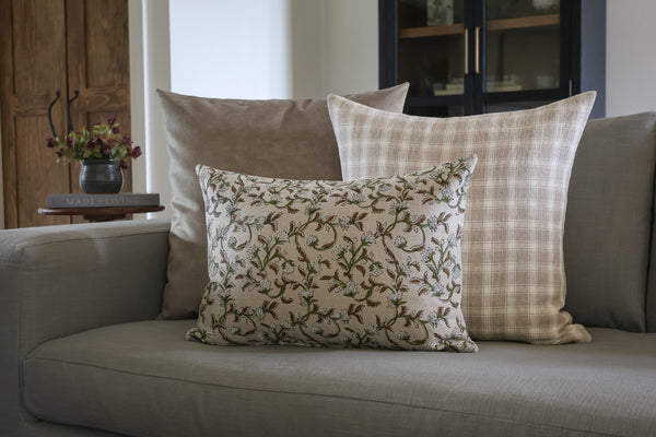 Neutral designer pillow cover set styled on a sofa, featuring a brown and green botanical block print lumbar pillow layered with beige plaid and soft taupe pillows by HACKNER HOME.