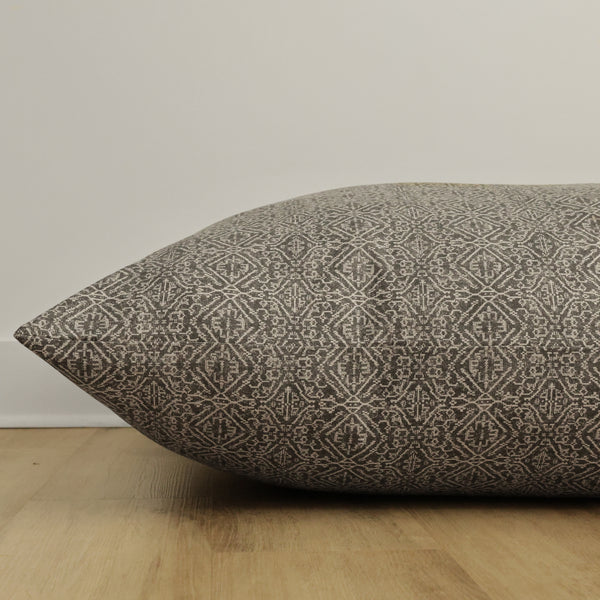 Side view of Hackner Home Acadia floor pillow cover showcasing its intricate geometric woven pattern in neutral tones on a wooden floor background.