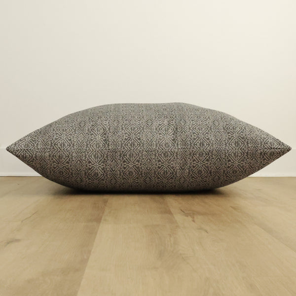 Side view of Hackner Home Acadia floor pillow cover showcasing its intricate geometric woven pattern in neutral tones on a wooden floor background.