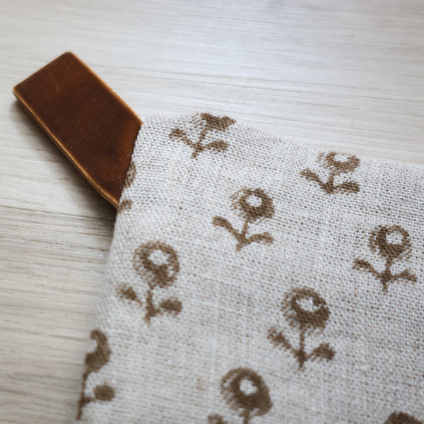 Large linen Christmas stocking with a minimalist brown floral block print pattern and a brown velvet hanging loop, displayed on a plain background.