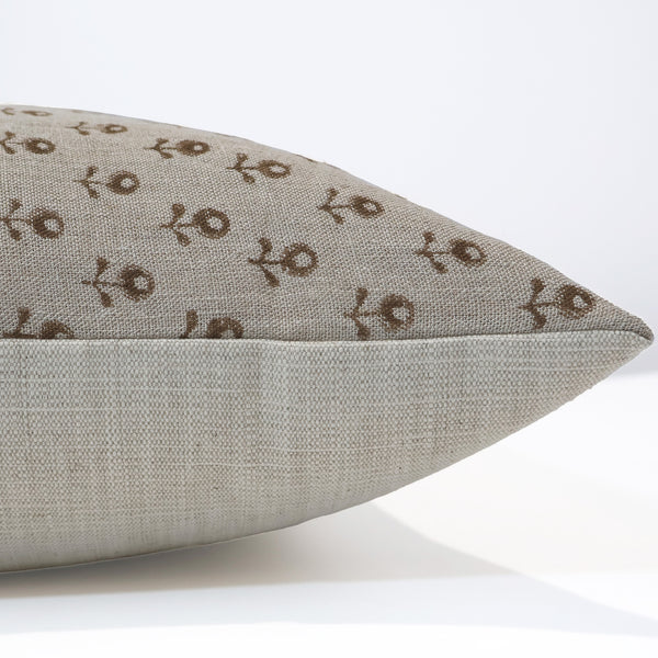 Side view of neutral linen pillow cover featuring a small brown floral block print pattern and solid textured backing.