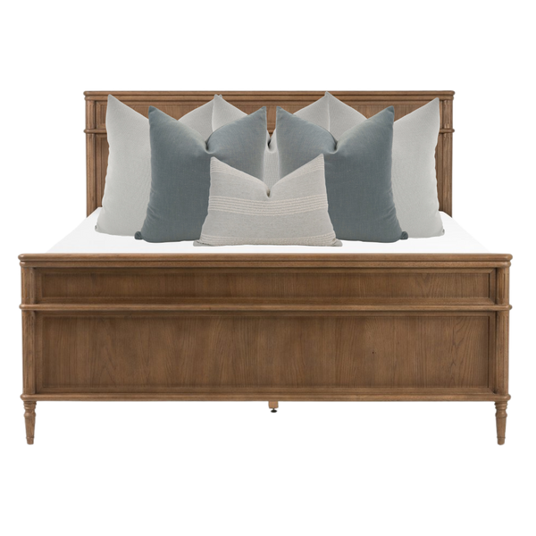 Hackner Home Moonlit Fog bed pillow combo styled on a wooden bed frame with layered blue-gray and ivory decorative pillows for a calm, elegant bedroom look.