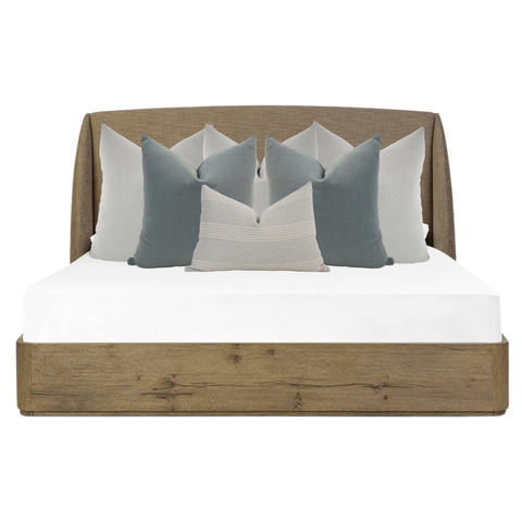 Hackner Home Moonlit Fog bed pillow combo featuring layered blue-gray and ivory decorative pillows on a rustic wood upholstered bed frame.