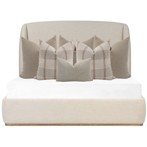 Hackner Home soft neutral bed pillow combo with beige plaid and textured decorative pillows styled on an upholstered cream bed frame.