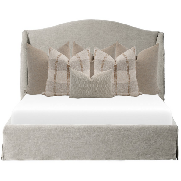 Hackner Home bed pillow combo in soft neutral layers featuring a mix of plaid and textured beige pillows styled on a linen-upholstered bed.
