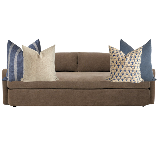 Neutral beige sofa styled with a cohesive mix of blue and cream Hackner Home pillow covers, featuring a balance of solid textures, stripes, and floral block prints for a timeless, coastal-inspired look.