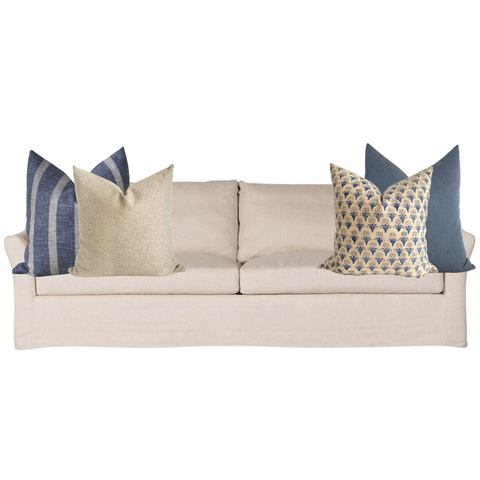 Neutral beige sofa styled with a cohesive mix of blue and cream Hackner Home pillow covers, featuring a balance of solid textures, stripes, and floral block prints for a timeless, coastal-inspired look.