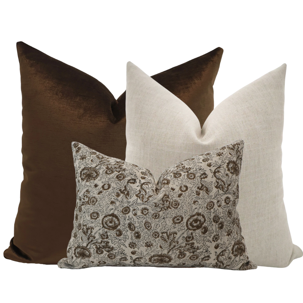 Hackner Home Clara Pillow Cover Set featuring a rich chocolate brown velvet pillow, a soft neutral linen pillow, and a floral block print lumbar pillow in warm brown tones.
