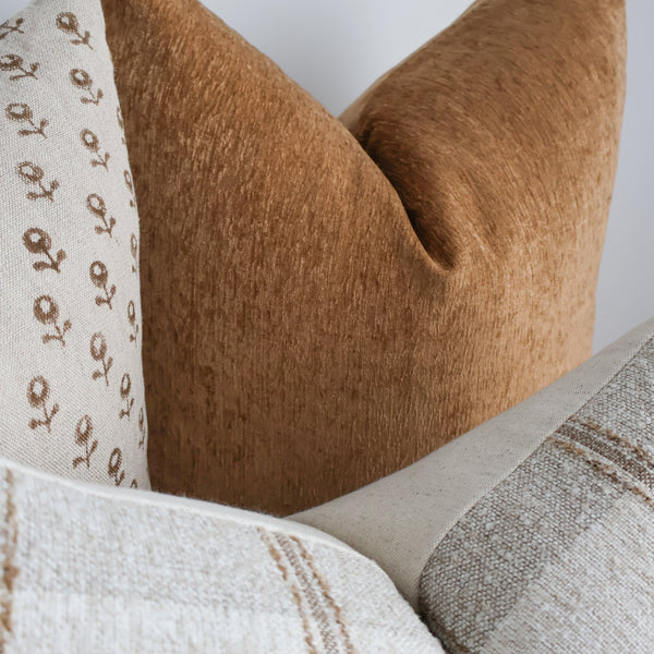 Close-up of Hackner Home Cottage Ember pillow covers showcasing soft brown chenille, floral linen, and striped woven textures in warm neutral tones.