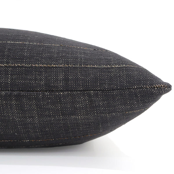 Close-up side view of Hackner Home Slate Sand outdoor pillow cover featuring dark charcoal woven fabric with subtle tan stitching for modern patio or indoor decor.