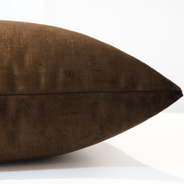 Side view of a deep brown velvet pillow cover showing its soft texture and subtle sheen.
