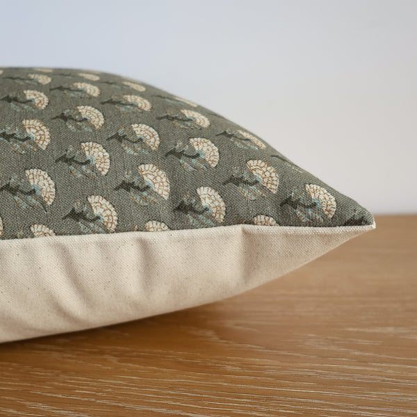Close-up side view of Hackner Home Green Meadow pillow cover featuring a sage green floral pattern with a neutral beige back, displayed on a wooden surface.