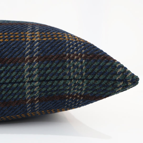 Close-up side view of a pillow cover with a heather and thistle plaid pattern in navy blue, green, mustard yellow, and brown, showing the textured woven fabric.