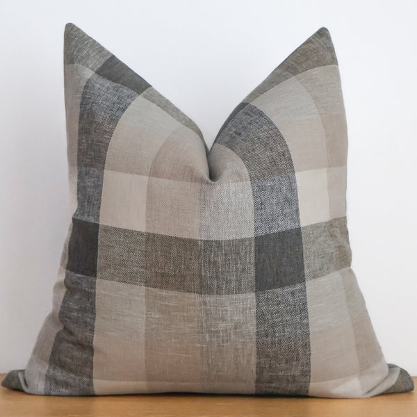 Hackner Home Ironwood plaid pillow cover displayed on a wooden table, featuring neutral beige and gray tones in a soft linen fabric.