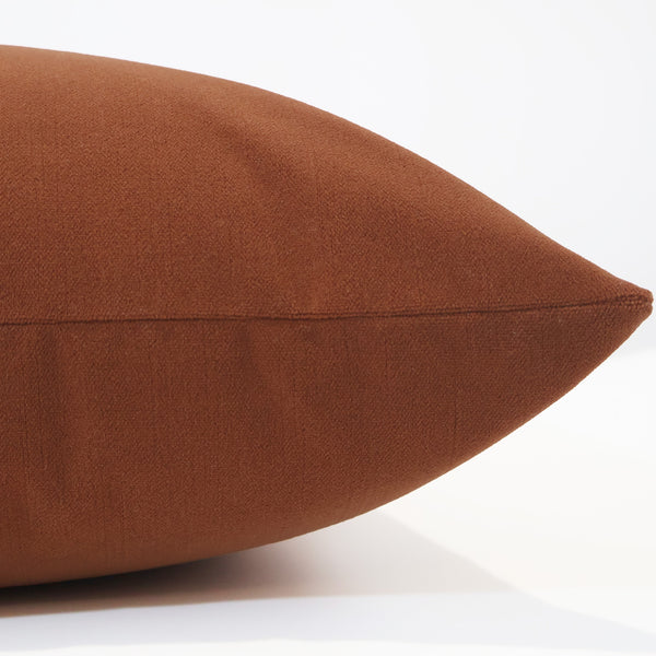 Side view of a pumpkin orange velvet pillow cover showing its smooth texture, rich color, and neatly stitched seam.