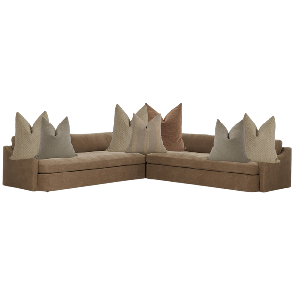 Modern brown sectional sofa styled with neutral throw pillows in beige, taupe, and clay tones — cozy living room corner seating.