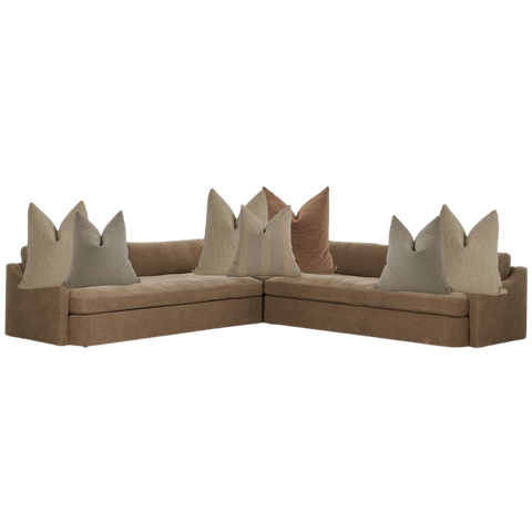 Modern brown sectional sofa styled with neutral throw pillows in beige, taupe, and clay tones — cozy living room corner seating.