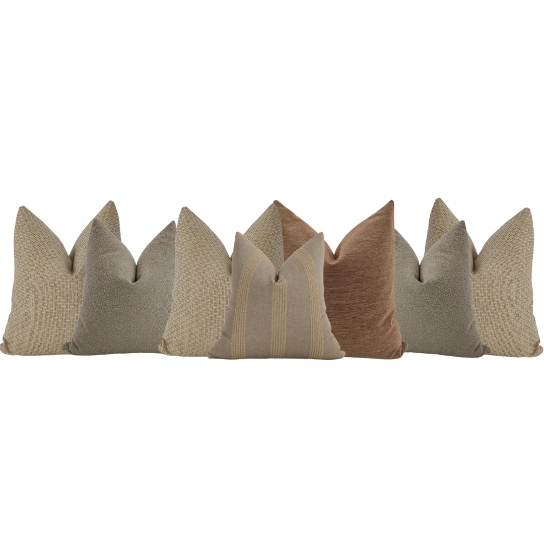 Modern brown sectional sofa styled with neutral throw pillows in beige, taupe, and clay tones — cozy living room corner seating.