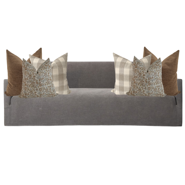 Gray upholstered sofa styled with six decorative pillows in earthy tones, featuring solid brown, beige plaid, and blue floral block print designs for a cozy autumn-inspired look.
