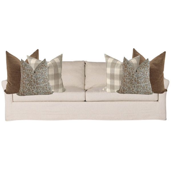Light beige sofa styled with six decorative pillows in warm earthy hues, featuring solid brown, neutral plaid, and soft blue floral block print designs for a cozy autumn-inspired arrangement.