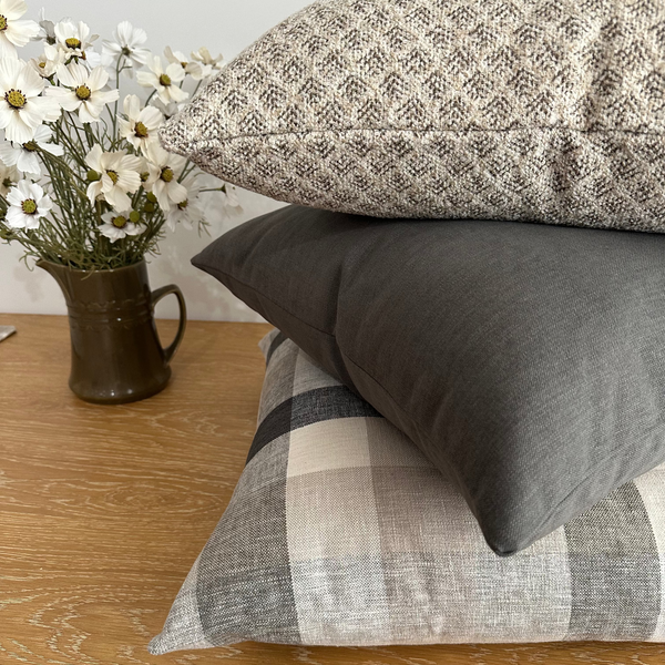Neutral gray and beige plaid pillow cover set from Hackner Home, featuring a mix of solid gray, checkered, and textured woven designs for a warm, modern farmhouse look.
