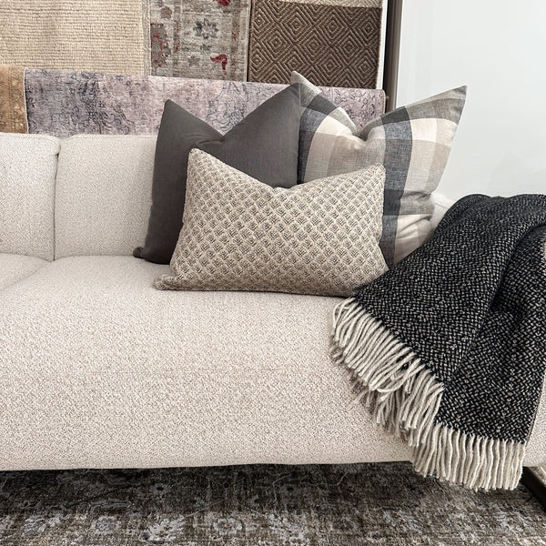 Hackner Home Timberland pillow cover set styled on a cream textured sofa with a black fringe throw blanket, featuring neutral gray and plaid pillows for a cozy modern look.